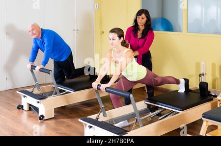 Femme hispanique pilates instructeur aidant la femme s'exerçant sur réformateur Banque D'Images