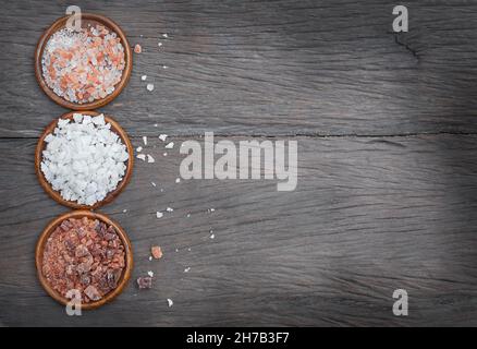 Three kinds of salt in wooden bowls on a wooden background Banque D'Images