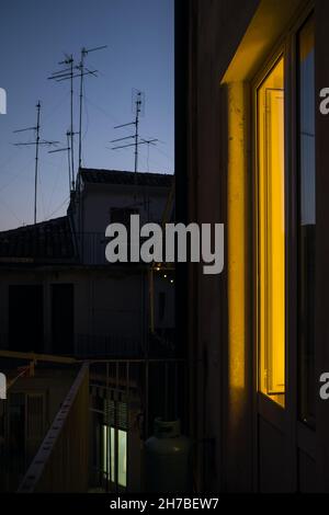 Lumière jaune chaude de la fenêtre de la maison au crépuscule. Banque D'Images