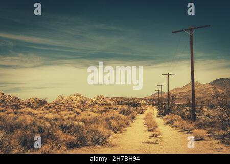 Mojave Desert Rural Sandy Road.Campagne du sud de la Californie thème avec poteaux électriques en bois. Banque D'Images