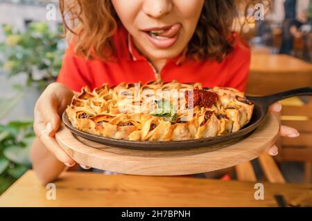 Femme léchant ses lèvres avant de manger de délicieux manti ou des boulettes sur une poêle à frire dans le restaurant.Cuisine traditionnelle des peuples oriental et turc Banque D'Images