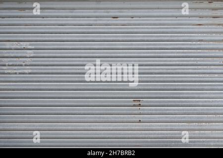 porte de garage en métal gris présentant des dommages légers dus à la rouille.Texture, arrière-plan. Banque D'Images