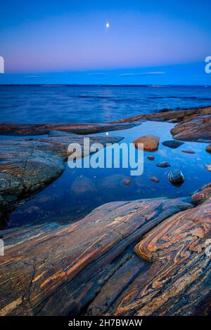 Lune et crépuscule le matin de novembre sur la côte rocheuse près du fjord d'Oslofjord, à Larkollen, Østfold, Norvège, Scandinavie. Banque D'Images