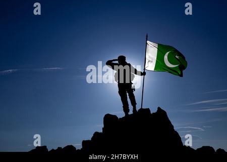 Silhouette d'un soldat méconnaissable au sommet de la montagne avec le drapeau pakistanais Banque D'Images