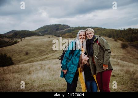 Portrait d'une petite fille avec mère et grand-mère debout et regardant les décors d'appareil photo dans la nature. Banque D'Images