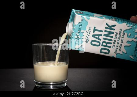 Boisson d'avoine sans lait le lait est versé d'une boîte dans un verre. Banque D'Images