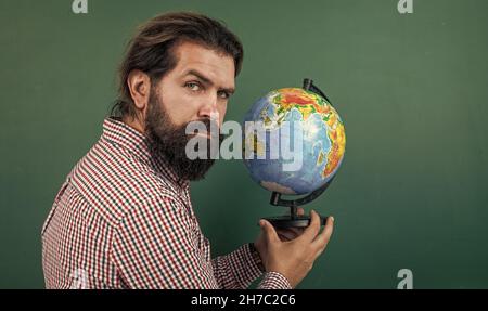 homme barbu mature enseignant en classe scolaire avec tableau noir, géographie Banque D'Images