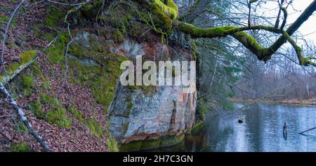 Les falaises long Ziedleju de 40 m sont composées de grès rougeâtres de la suite Gauja.Un affleurement de grès sur les rives de la rivière Gauja, Incukalns, Lettonie. Banque D'Images