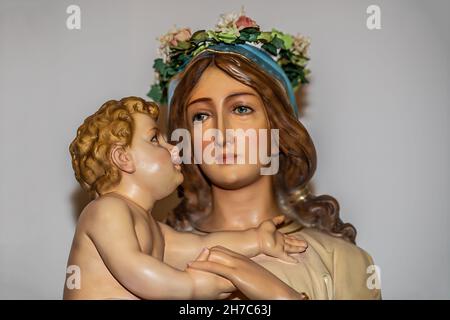 Gros plan de Marie tenant le bébé Jésus avec une couronne de fleurs sur la tête de Marie pour célébrer le mois de mai à l'église catholique Saint-Joseph. Banque D'Images