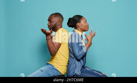 Homme et femme frustrés assis dos à dos et ayant des arguments en studio.Couple dans le conflit de combat et de discuter en raison de problèmes de relation.Personnes exprimant des émotions. Banque D'Images