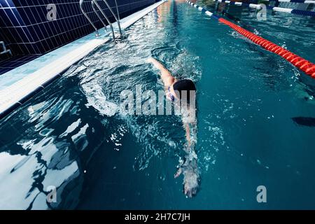 Jeune homme professionnel nageur, course de natation piscine intérieure, vue de dessus. Banque D'Images
