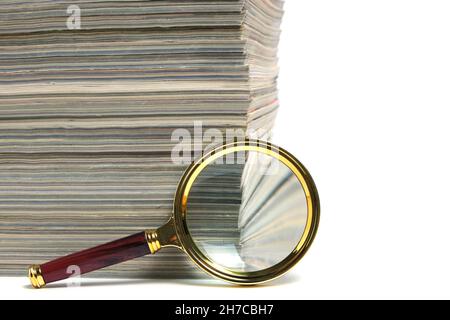 Pile de magazines et loupe sur fond blanc.concept de l'apprentissage et de la poursuite de la connaissance Banque D'Images