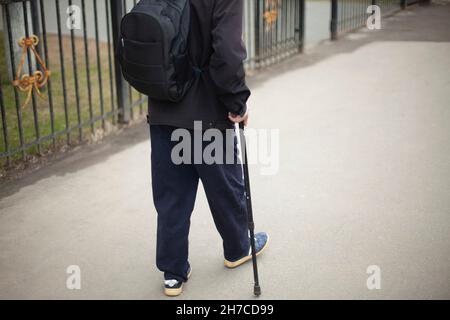 Un homme avec un poteau lors de la marche.Un retraité en Russie descend la rue.Un homme avec un sac à dos dans des vêtements chauds. Banque D'Images