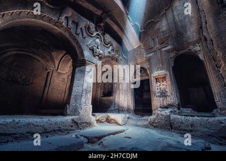 Intérieur du célèbre monastère de Geghard et église sculptée dans le rocher.Un rayon de lumière illumine un bas-relief ancien représentant des lions dans le hall Banque D'Images