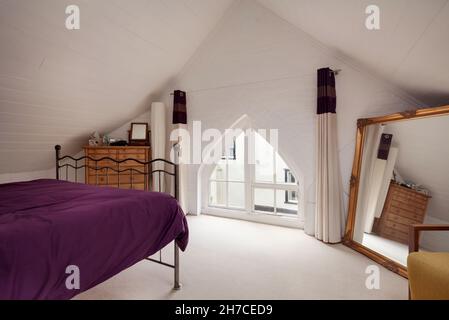 Stradishall, Suffolk, Angleterre - 16 juin 2020 : chambre mansardée de style loft avec murs peints en blanc et literie mauve Banque D'Images