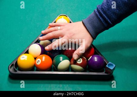 Boules de billard sur la table de billard verte avec la main d'un joueur dessus Banque D'Images