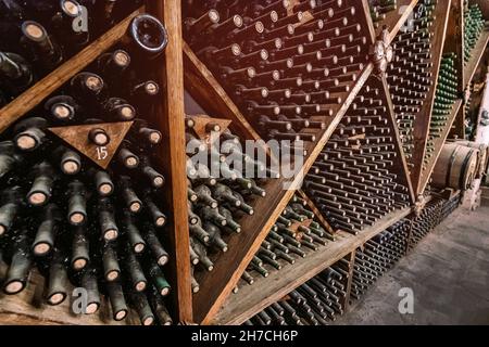 Il y a beaucoup d'étagères avec de vieilles bouteilles de vin couvertes de poussière dans la cave à vin ancienne du domaine. Banque D'Images