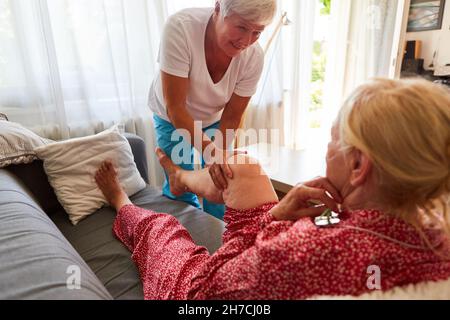 Le physiothérapeute traite l'arthrose du genou de la personne âgée dans une clinique de réadaptation ou à la maison Banque D'Images