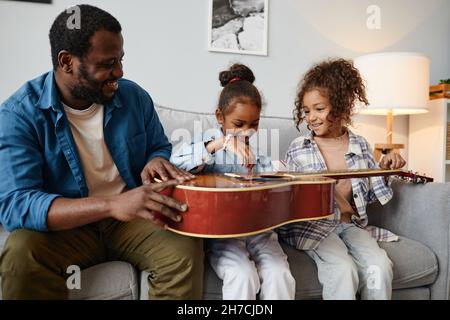 Portrait d'un père afro-américain heureux jouant avec deux jolies filles à la maison Banque D'Images