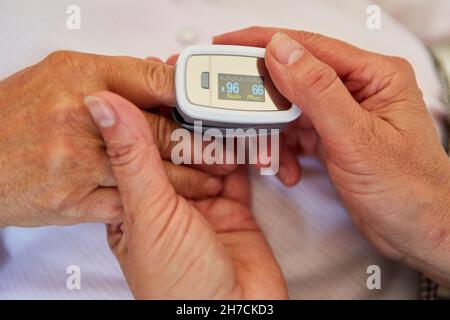 Mains du médecin tenir la main d'un patient âgé ayant un oxymètre de pouls à l'hôpital ou à la maison de retraite Banque D'Images