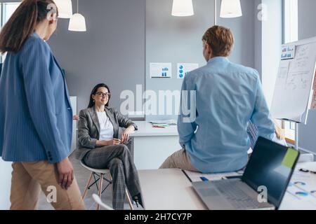 Le groupe d'employés se réunit de façon informelle au bureau et bavarde. Banque D'Images