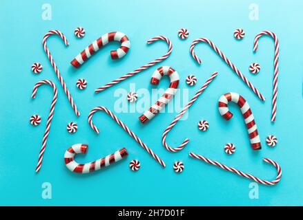 Bonbons de Noël sur fond bleu pastel.Concept joyeux Noël.Menthe poivrée rouge blanc rayé traditionnel bonbons enfants plat, motif. Banque D'Images