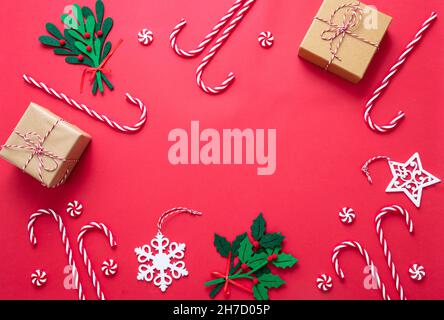 Cadre décoratif de Noël sur fond rouge.Cadeaux, baubles et Cannes de bonbons à plat.Modèle de carte de vœux pour le nouvel an de Noël, vue du dessus Banque D'Images