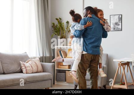Vue arrière portrait d'un père afro-américain heureux tenant deux filles mignonnes à la maison, espace copie Banque D'Images