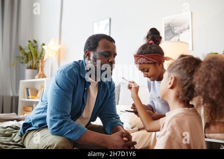 Portrait de deux petites filles mettant le maquillage sur le papa et souriant Banque D'Images