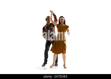Portrait dynamique de danseurs élégants, jeune homme et femme en tenue vintage dansant balançoire isolée sur fond blanc Banque D'Images