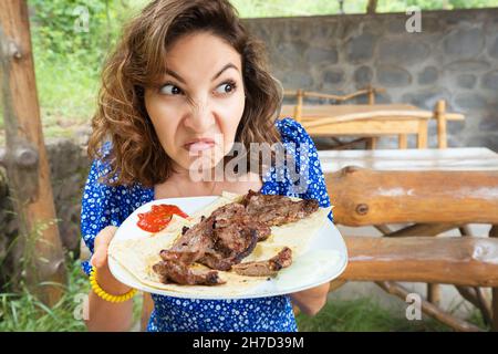 Une femme a un steak gâté dans un restaurant.Le concept de souffrir de l'anorexie ou d'un trouble de l'alimentation et la perte de sens de l'odorat après le covid. Banque D'Images