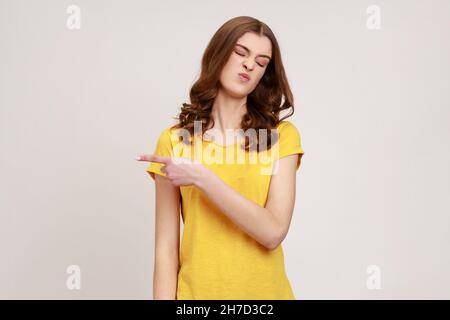 Sortez.Portrait de la femme contrariée bouleversée de jeune âge avec des cheveux ondulés montrant la sortie, exigeant de la laisser seule, a une expression irritée ranceuse.Prise de vue en studio isolée sur fond gris. Banque D'Images