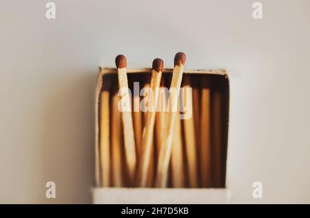 Dans une boîte d'allumettes en carton simple, il y a des allumettes en bois avec des têtes en soufre brun.Articles ménagers.Objets inflammables.Macro.Trois allumettes sortent de Banque D'Images