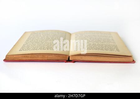Vieux livre ouvert isolé avec texte flou sur les pages en difficulté, tourné d'un angle bas Banque D'Images