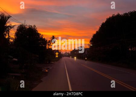 La belle silhouette se coucher au-dessus de la route asphaltée et de l'environnement Banque D'Images