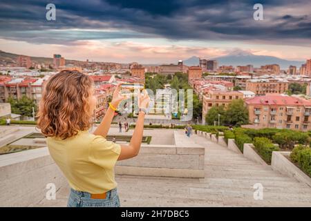 Bonne femme prenant des photos d'un paysage urbain pittoresque dans la ville d'Erevan avec une vue lointaine sur le célèbre Mont Ararat et le complexe de Cascade Banque D'Images