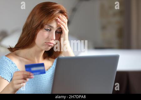 Femme frustrée ayant des problèmes de paiement en ligne avec carte de crédit et ordinateur portable dans la chambre Banque D'Images