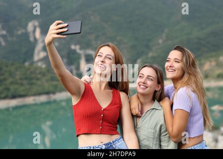 Des amis heureux prenant le selfie avec un smartphone pendant les vacances d'été dans un lac Banque D'Images