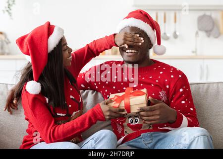 Femme noire aimante donnant à son mari cadeau de Noël Banque D'Images
