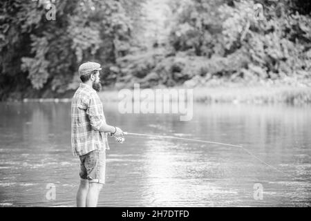 ne regardez pas en arrière. pêcheur expérimenté dans l'eau. pêcheur montrer technique de pêche utiliser tige. homme attrapant poisson. homme mature pêche à la mouche. activité sportive et Banque D'Images