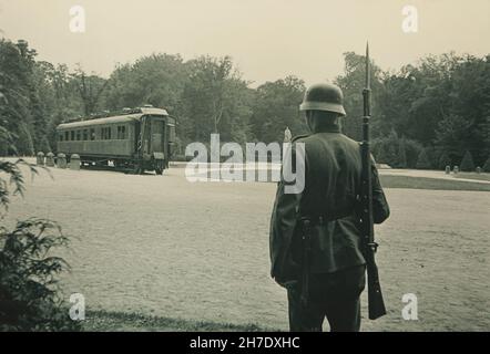 Le soldat allemand garde à côté du chariot de Compiègne du Maréchal Ferdinand Foch au sol de la Glade de l'Armistice dans la Forêt de Compiègne (Forêt de Compiègne)En juin 1940, sur le site où l'armistice du 11 novembre 1918 qui a mis fin à la première Guerre mondiale a été signé.L'armistice du 22 juin 1940 après que l'Allemagne ait gagné la bataille de France a également été signé au même endroit dans le même wagon.L'original du chariot de Compiègne a été détruit en feu en avril 1945 pendant la Seconde Guerre mondialePhotographie vintage en noir et blanc d'un photographe inconnu datée du 1940 juin sur dis Banque D'Images