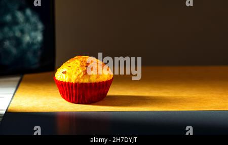 un cupcake est photographié avec une petite lumière dans le studio sur un fond de papier ancien.Cuisine maison Banque D'Images