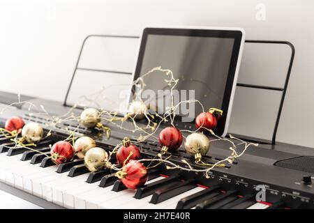 Composition du nouvel an sur un synthétiseur musical. Lumières d'une guirlande.Carte de vœux de joyeux Noël.Bonne Année. Banque D'Images