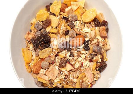 Mélange de flocons d'avoine avec de nombreuses variétés de fruits pour le petit déjeuner dans un bol blanc, isolé sur fond blanc Banque D'Images