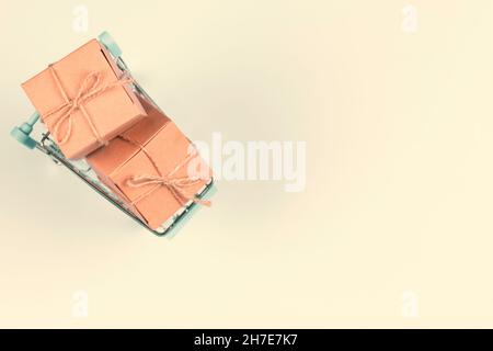 Vue de dessus à mini panier avec petit papier kraft présente boîtes-cadeaux sur fond pastel.E-commerce, concept d'achat en ligne Banque D'Images