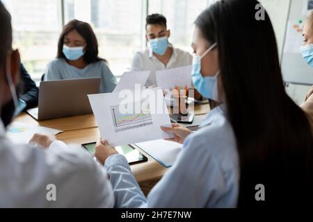 Équipe d'affaires portant des masques médicaux pendant la réunion d'entreprise au bureau Banque D'Images