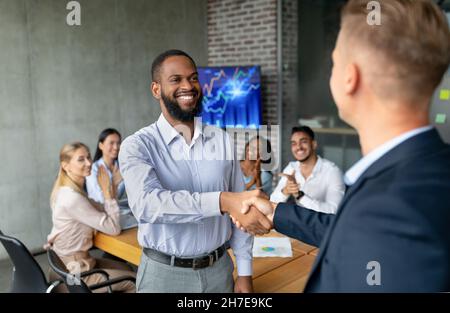 Le PDG de la société, en compagnie d'un homme afro-américain, saluant un nouvel employé au bureau Banque D'Images