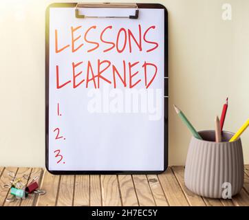 Texte d'écriture leçons apprises.Word for Experiences projet distillé qui devrait activement prendre Plain Office Clipboard avec des piles de stylos dans Un Banque D'Images