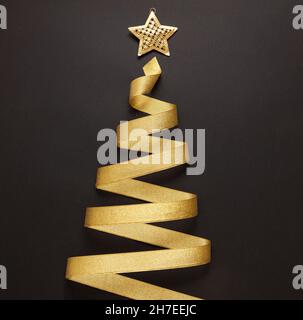 Ruban doré en forme d'arbre de Noël sur fond noir.Étoile dorée brillante sur le dessus.Modèle de carte de vœux Joyeux Noël et joyeux nouvel an Banque D'Images