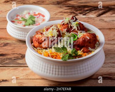 Poulet Tikka Biryani fait de riz Basmati cuit avec des épices de masala, servi avec du yaourt, concentré sélectif Banque D'Images